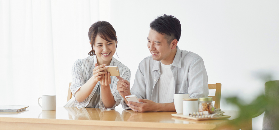 ダイニングでスマホを見ている夫婦の画像です