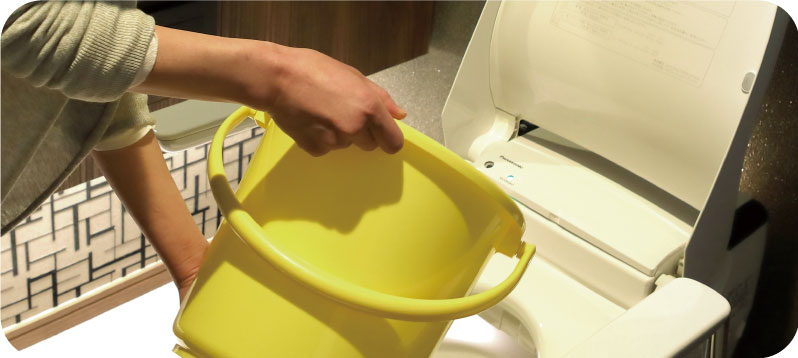 写真:バケツでトイレに水を流している