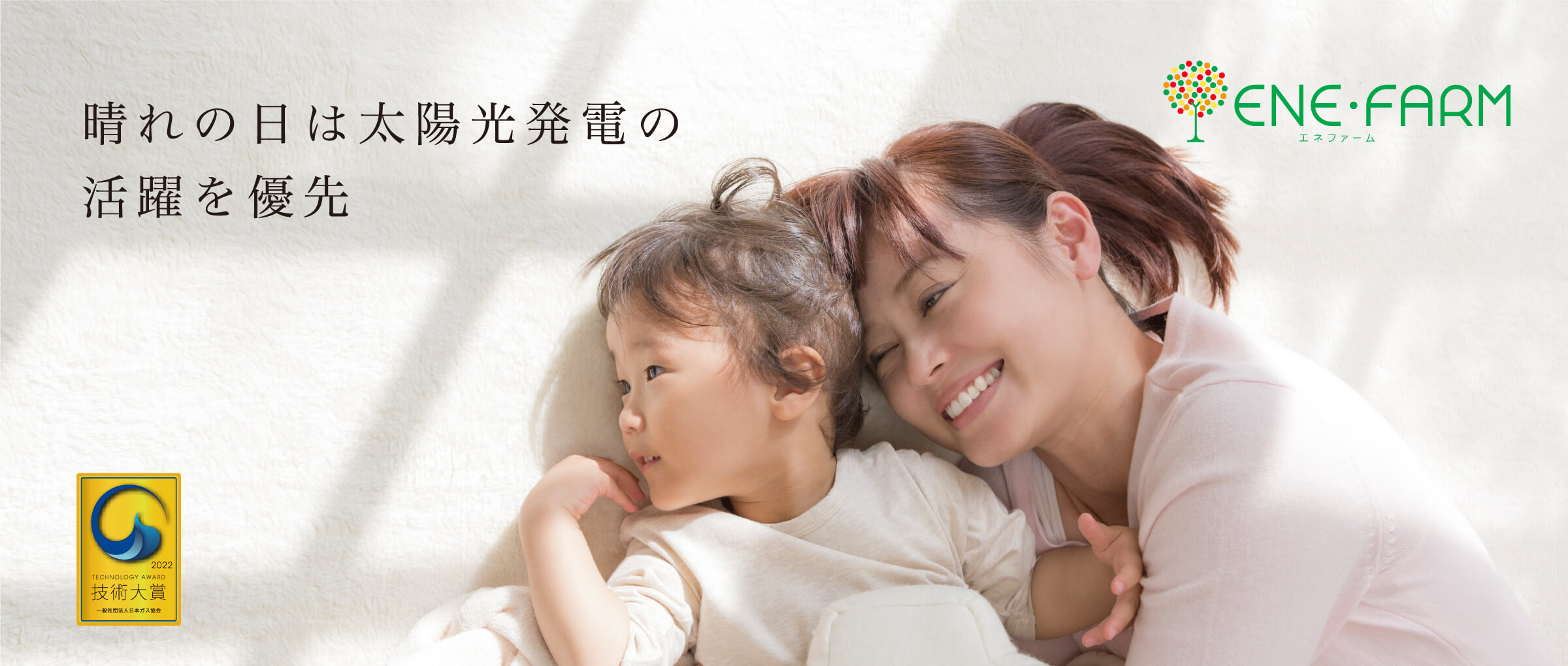おてんき連動のご紹介ページのメインビジュアルです。絨毯の上で日向ぼっこしている親子の画像です。おてんき連動では、晴れの日は太陽光発電の活躍を優先させることができます。