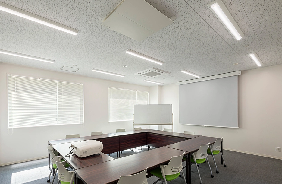 iDシリーズ照明で均一に照らされた、机と椅子が並ぶ会議室。