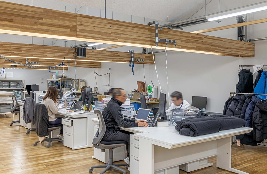 ファクトラインからの電源共有により、整理された配線環境で事務作業をする縫製工場のスタッフ