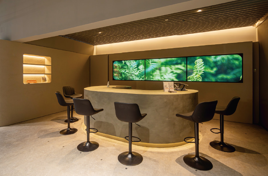 同受付カウンターはTOLSOユニバーサルダウンライトと間接照明の組み合わせで映像演出も引き立つ光環境を実現